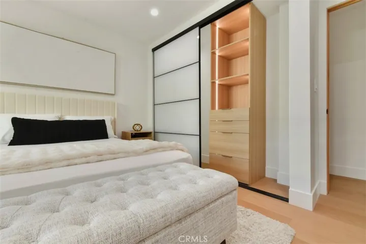  Alternate bedroom view showcasing direct closet access and integrated wood shelving units.