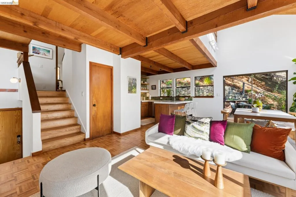 Exposed timber ceiling beams, parquet wood-finish flooring, sliding glass door, and wooden staircase with open railing