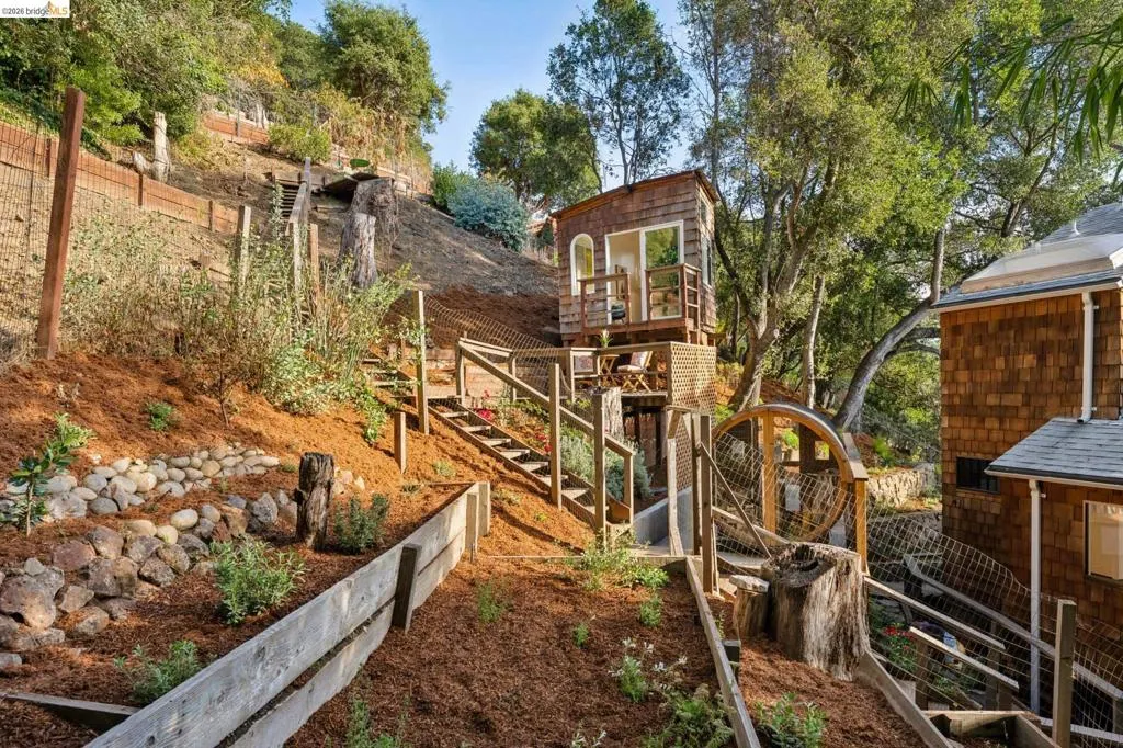 Terraced hillside landscaping with stone retaining walls, wood-shingle exterior siding, and integrated wooden staircase