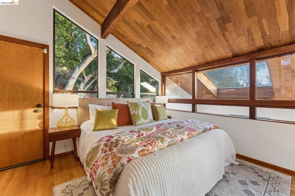 Vaulted wood-paneled ceiling with exposed structural beam, expansive floor-to-ceiling windows, and integrated skylight