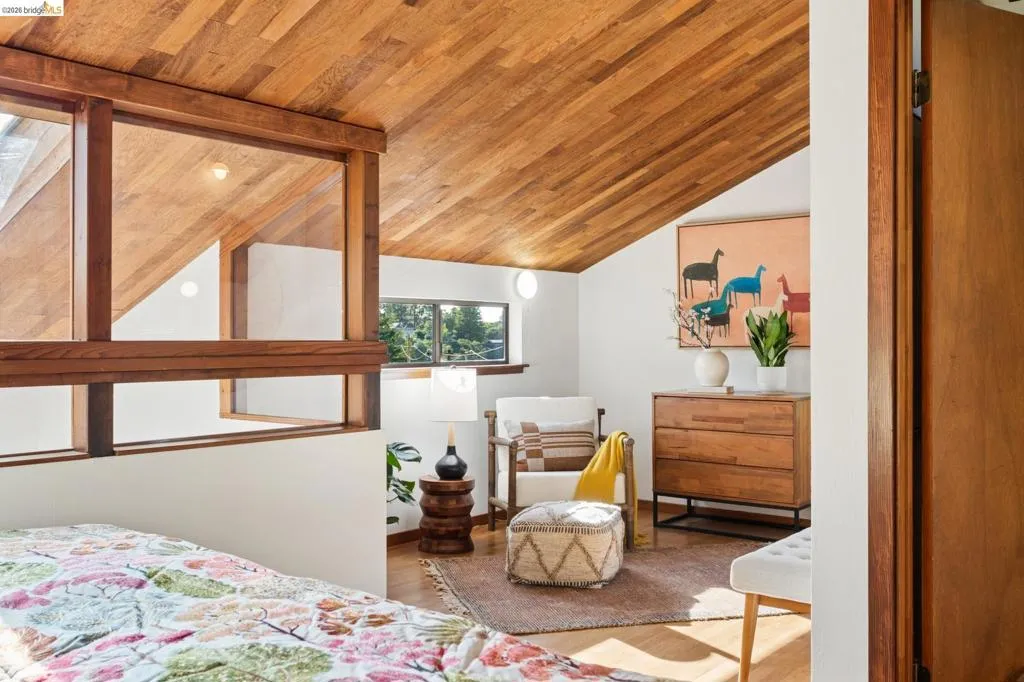 Vaulted ceiling with wood-plank paneling, integrated wood-framed partition wall, wood-finish flooring, and horizontal picture windows