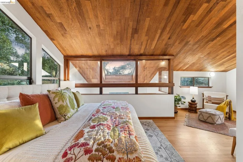 Vaulted ceiling with wood-plank paneling, large-format glass windows, built-in horizontal interior window partitions, and wood-finish flooring