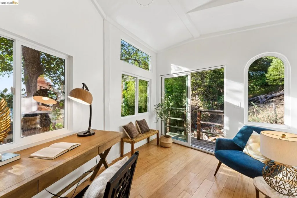 Vaulted ceiling, wood-finish flooring, multi-pane windows, arched window detail, and glass sliding door