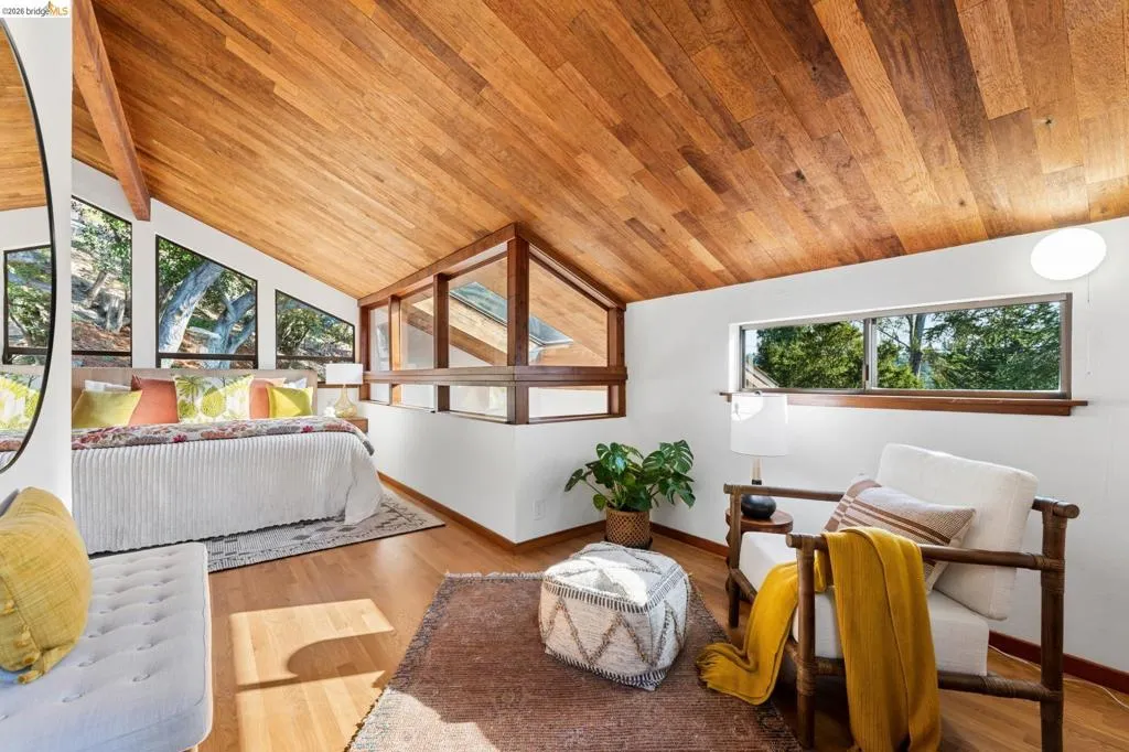 Vaulted tongue-and-groove wood ceiling, large multi-pane windows, and wood-finish flooring