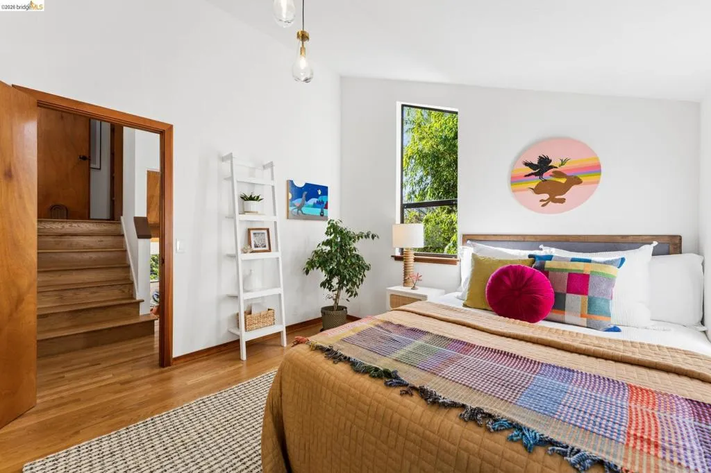 Vaulted ceiling, wood-finish flooring, wood-framed interior doorway, pendant lighting, and multi-pane window