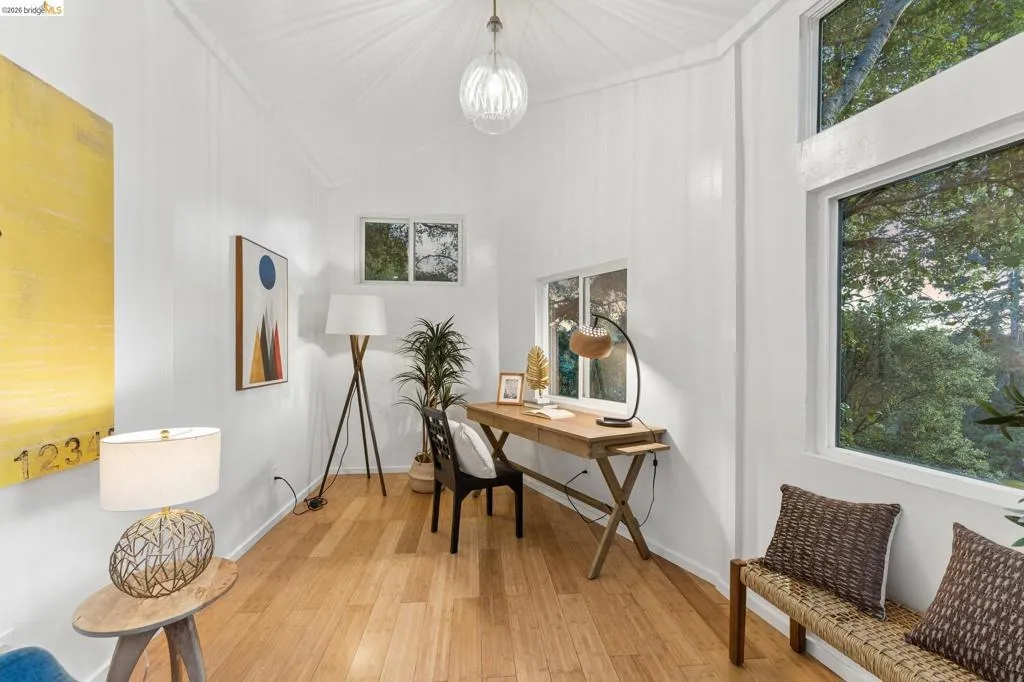 Vaulted ceilings with board-and-batten wall detailing, wood-finish flooring, glass globe pendant lighting, and multi-pane windows