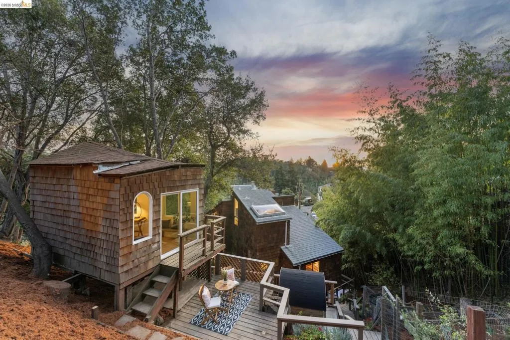 Wood shingle siding exterior featuring an elevated wood deck, an arched window, sliding glass doors, and a skylight