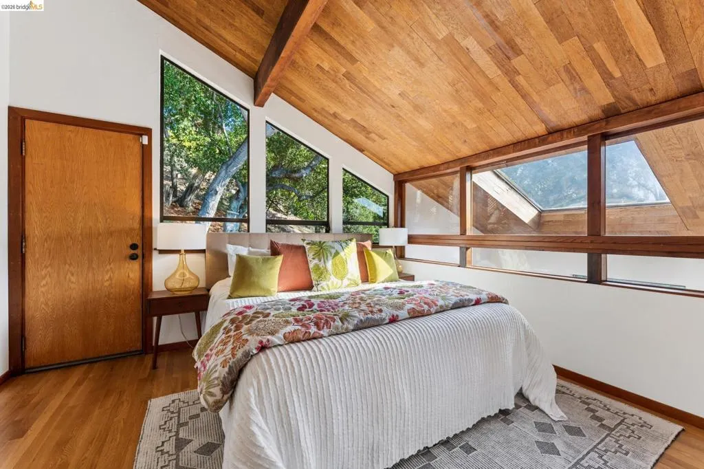 Vaulted wood-paneled ceiling, expansive windows, skylight, and wood-finish flooring