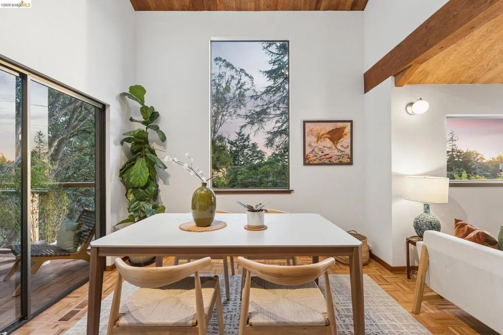 Vaulted ceilings with exposed wooden beams, parquet wood-finish flooring, floor-to-ceiling windows, and sliding glass doors