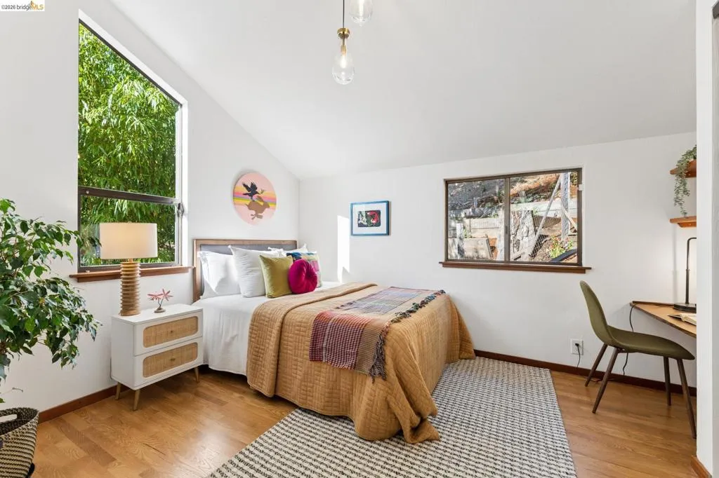 Vaulted ceiling, wood-finish flooring, dual-aspect windows, and a built-in wall-mounted desk