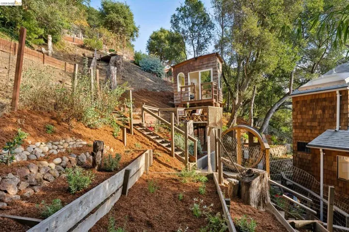 Terraced hillside landscaping with stone retaining walls, wood-shingle exterior siding, and integrated wooden staircase