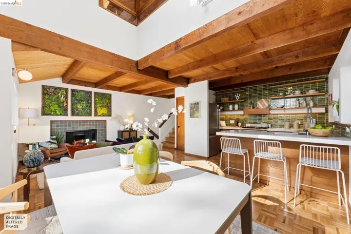 Vaulted ceilings featuring exposed wood beams, parquet flooring, a fireplace with decorative tile surround, and a kitchen equipped with a breakfast bar and green tile backsplash