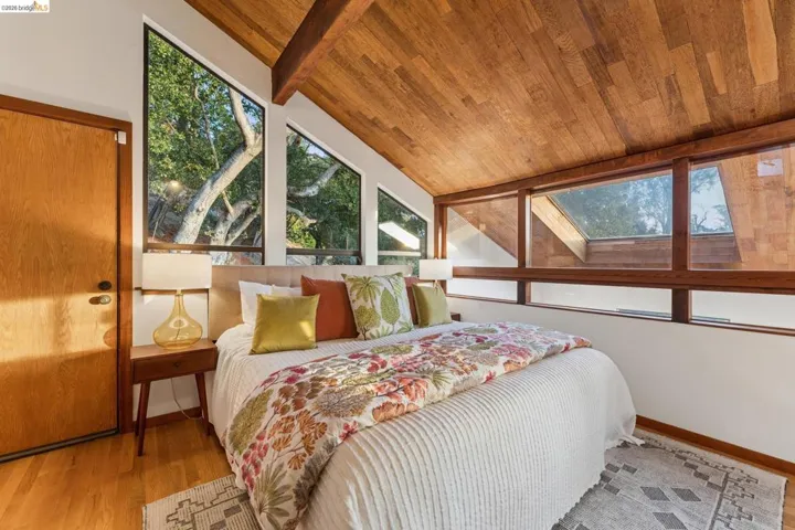 Vaulted wood-paneled ceiling with exposed structural beam, expansive floor-to-ceiling windows, and integrated skylight