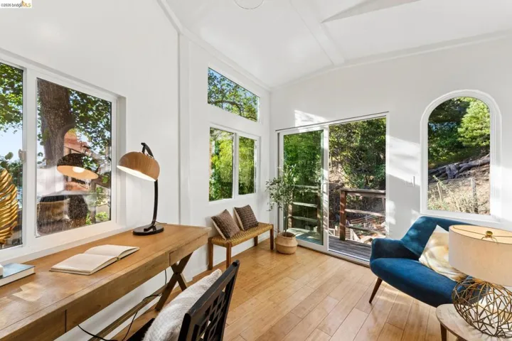 Vaulted ceiling, wood-finish flooring, multi-pane windows, arched window detail, and glass sliding door