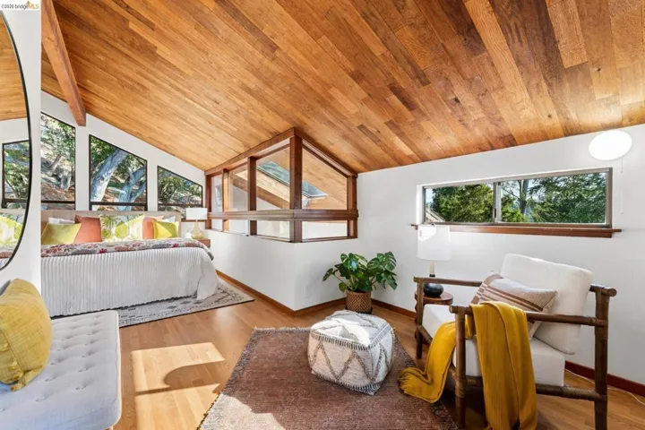 Vaulted tongue-and-groove wood ceiling, large multi-pane windows, and wood-finish flooring