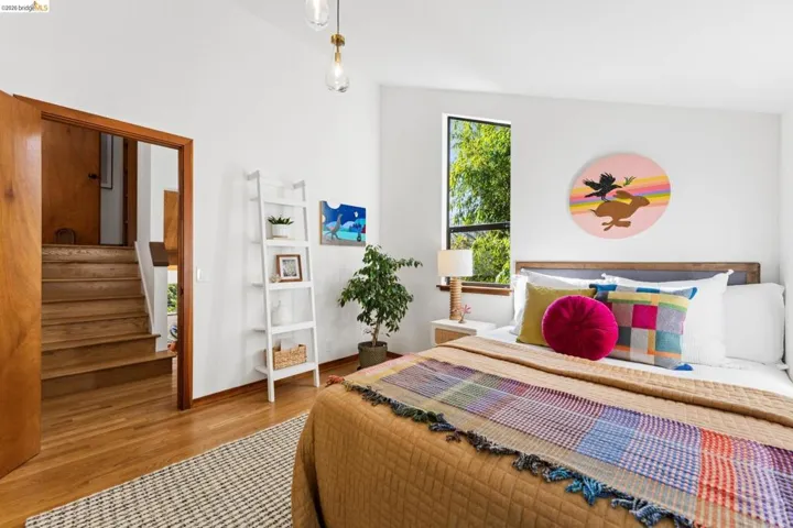 Vaulted ceiling, wood-finish flooring, wood-framed interior doorway, pendant lighting, and multi-pane window