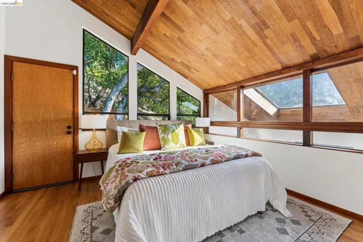 Vaulted wood-paneled ceiling, expansive windows, skylight, and wood-finish flooring
