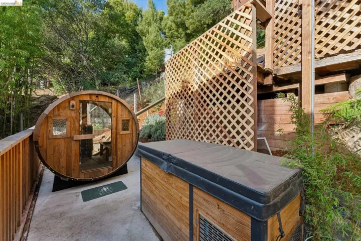 Outdoor terrace featuring a barrel-style wood sauna, a covered hot tub, and decorative wood lattice privacy screening
