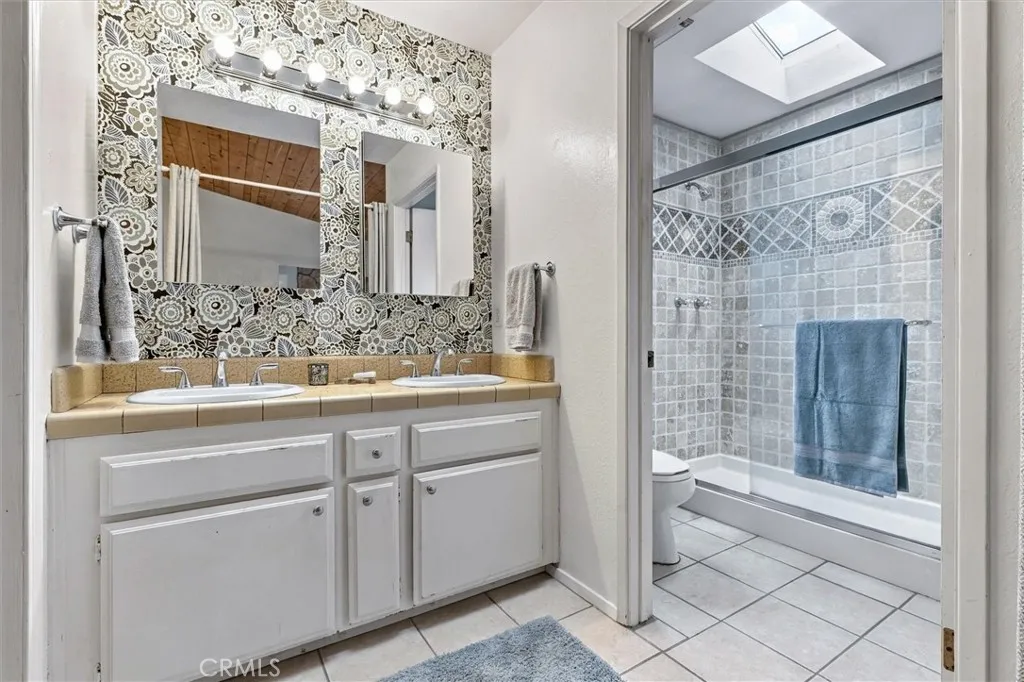 Whimsical and artsy tile work and wall paper are great touches in the primary bath which has a skylight right over the shower. Whimsical and artsy tile work and wall paper are great touches in the primary bath which has a skylight right over the shower.