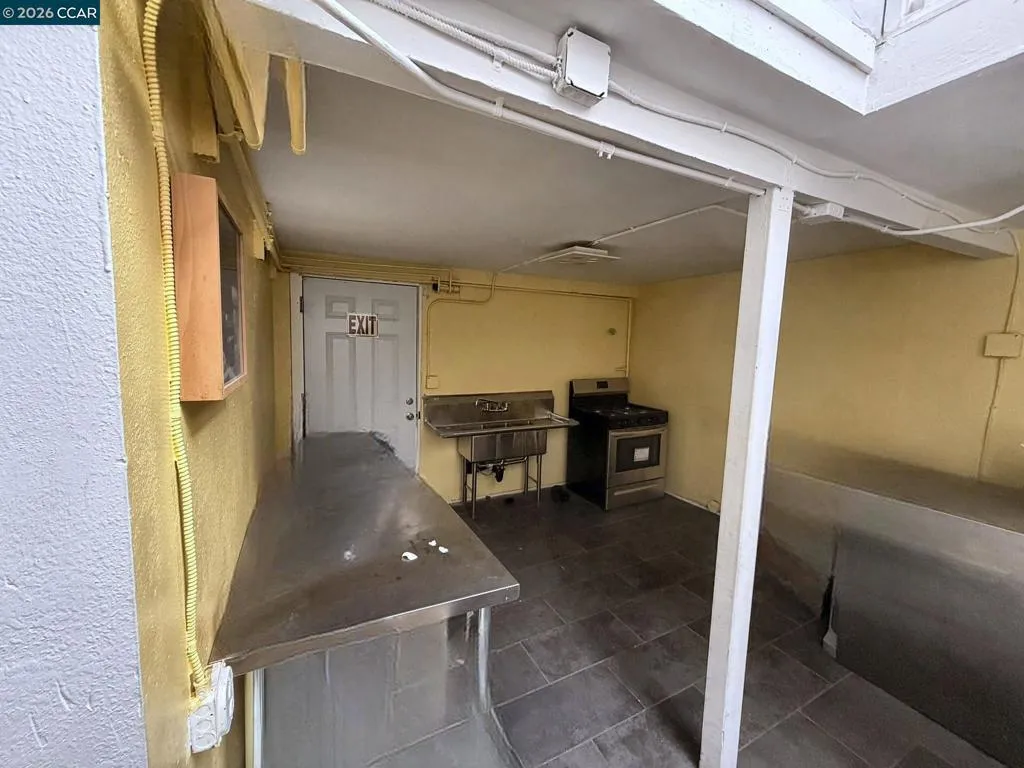 Lower level: kitchen area with 3-compartment sink. Digitally altered: personal property and debris removed. Unaltered photo available.