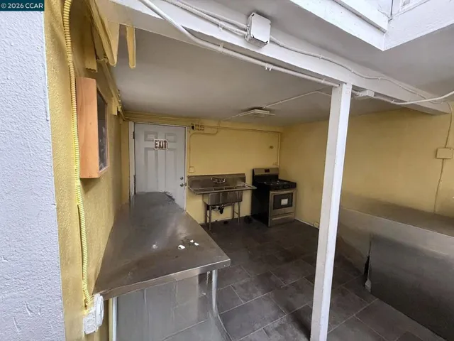 Lower level: kitchen area with 3-compartment sink. Digitally altered: personal property and debris removed. Unaltered photo available.