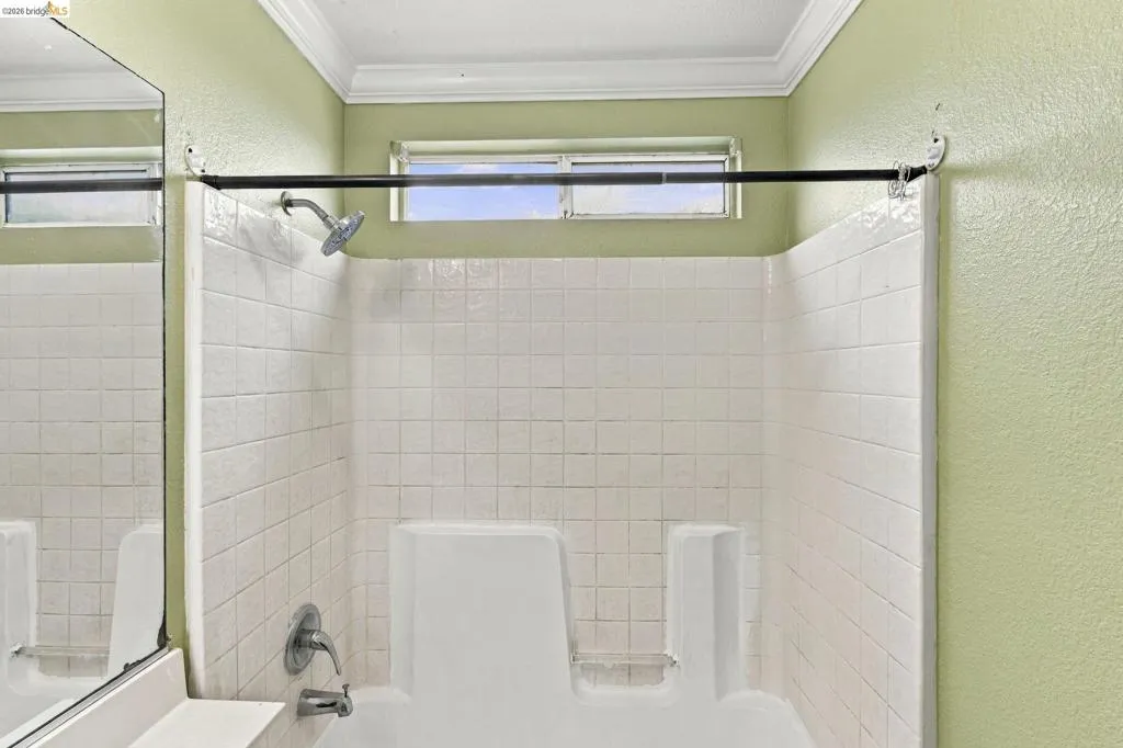Tub and shower combination with square tile surround, wall-mounted showerhead, single-handle faucet, and horizontal transom window