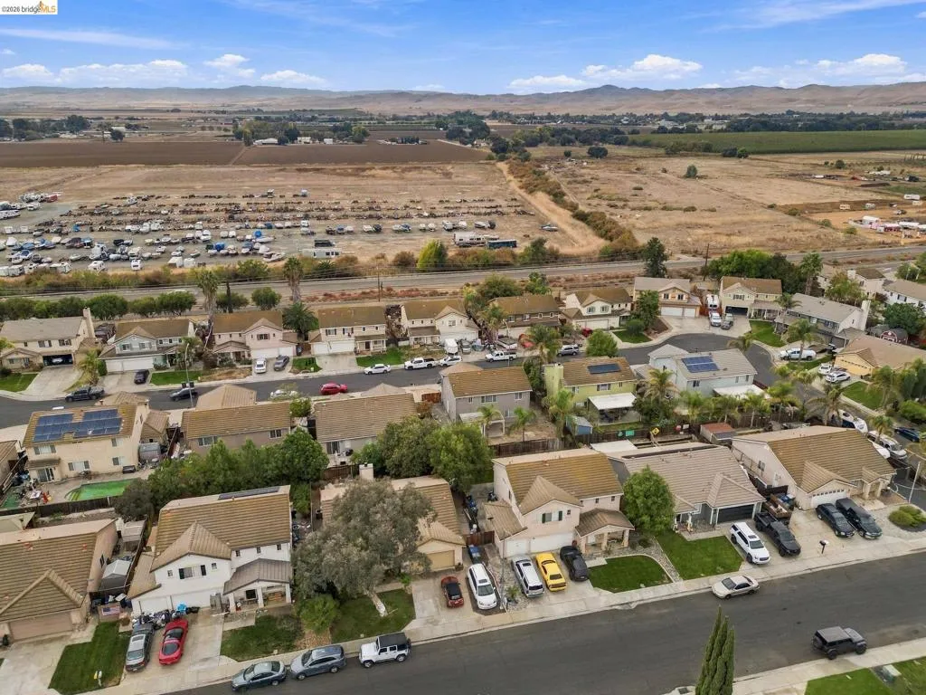 Aerial perspective of a suburban neighborhood featuring multi-story dwellings, paved cul-de-sacs, mature landscaping, and a distant mountain backdrop