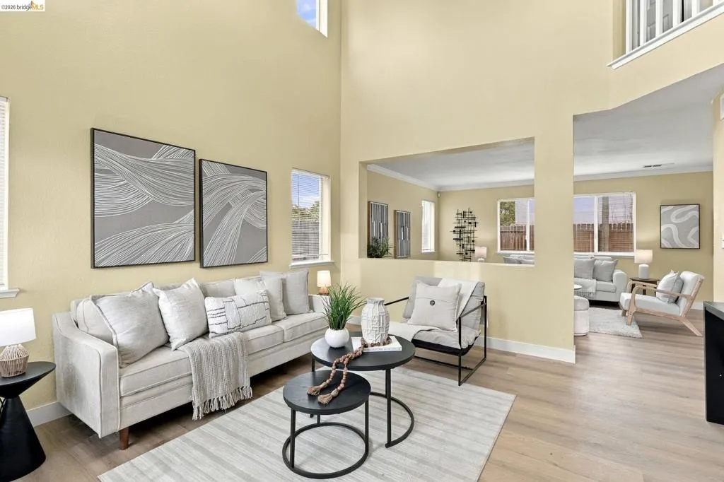 Double-height ceiling, wood-finish flooring, and large windows providing natural light