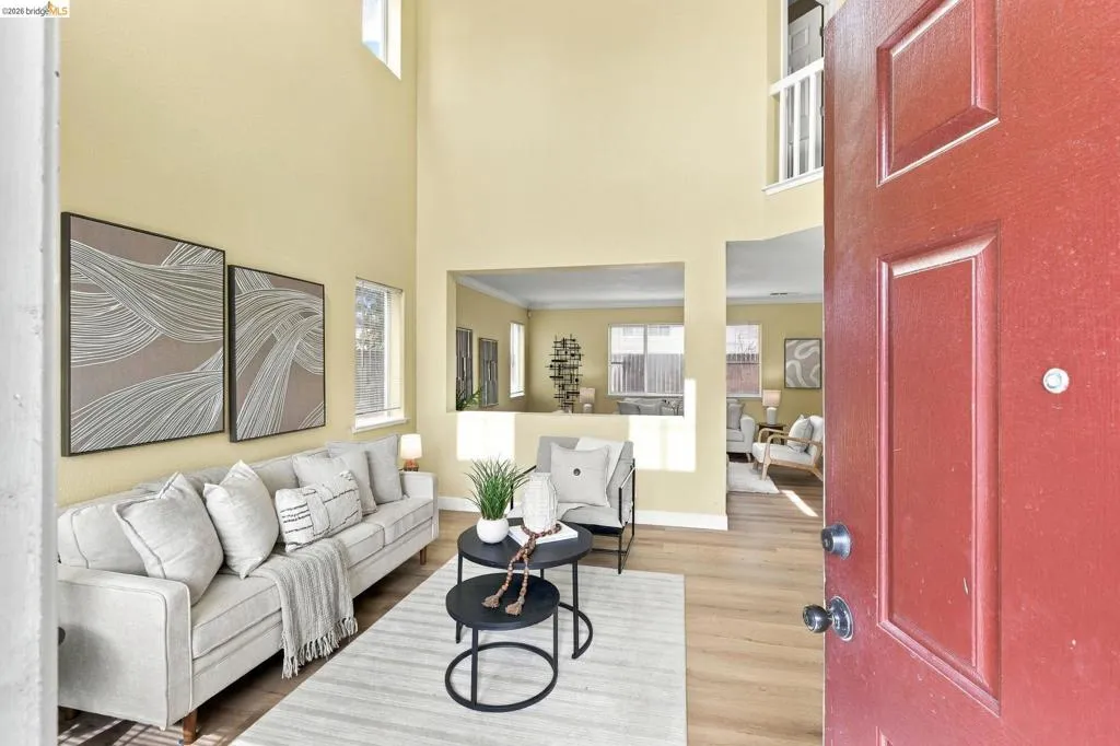 Entryway featuring double-height vaulted ceilings, wood-finish flooring, and a structural pass-through window looking into the secondary interior space