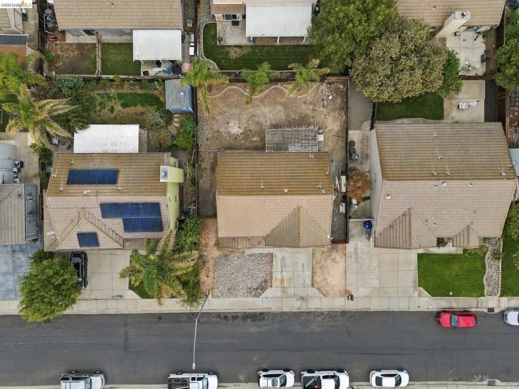 Aerial perspective of a property featuring a concrete driveway, multi-gabled roofline, and rear yard area