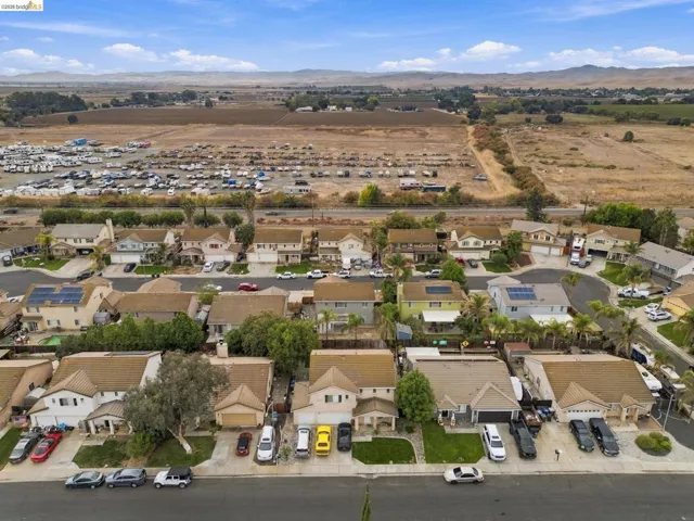 Aerial perspective of suburban residential neighborhood featuring multi-story homes with composition shingle roofs, integrated garages, solar panel installations, and landscaped front yards