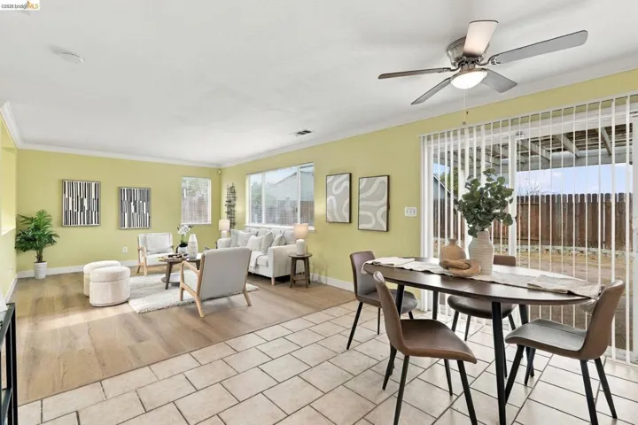 Wood-finish flooring, neutral tile flooring, ceiling-mounted fan with integrated lighting, and sliding glass patio doors