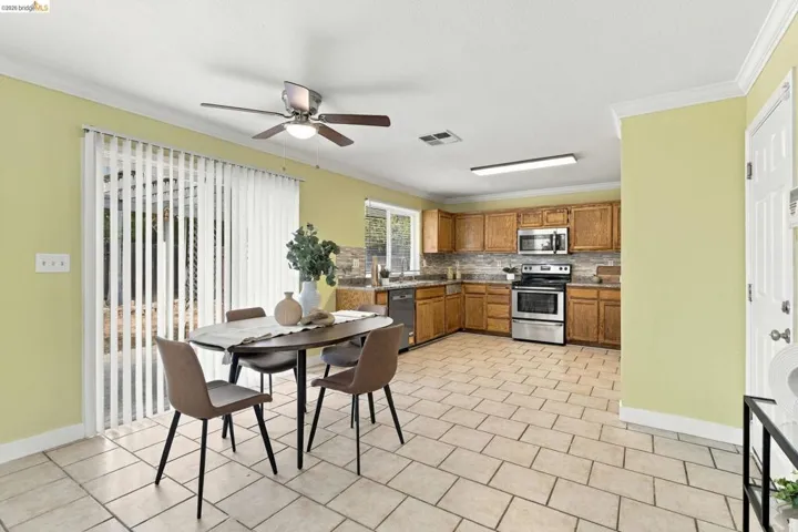 Kitchen featuring wood cabinetry, stainless steel appliances, tile flooring, crown molding, and sliding glass doors