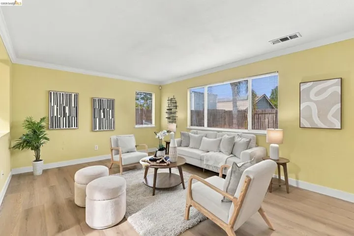 Living area featuring wood-finish flooring, crown molding, and large picture windows