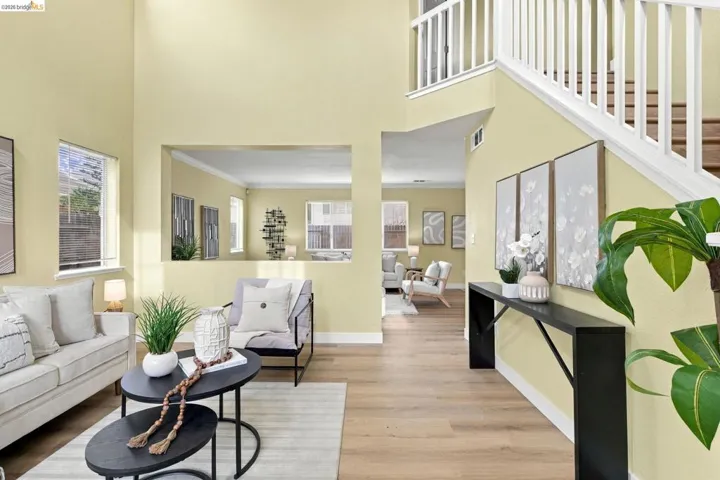 Double-height ceilings, wood-finish flooring, staircase with white railing, and architectural wall cutout