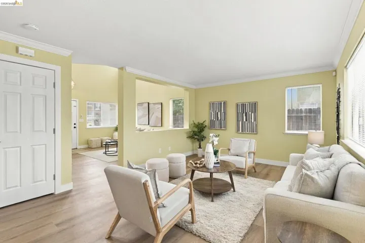 Open-concept interior featuring wood-finish flooring, multi-pane windows, crown molding, and a pass-through wall cutout