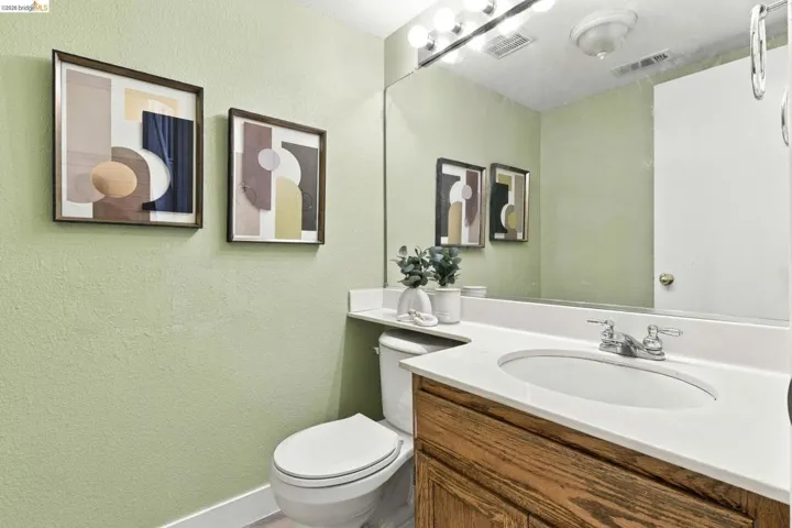 Wood-finish vanity, white countertop with integrated oval sink, full-width vanity mirror, and polished chrome light fixture