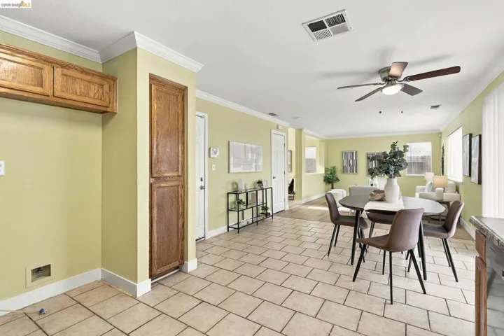 Dining area featuring tile flooring, built-in cabinetry, crown molding, and a ceiling fan with integrated lighting