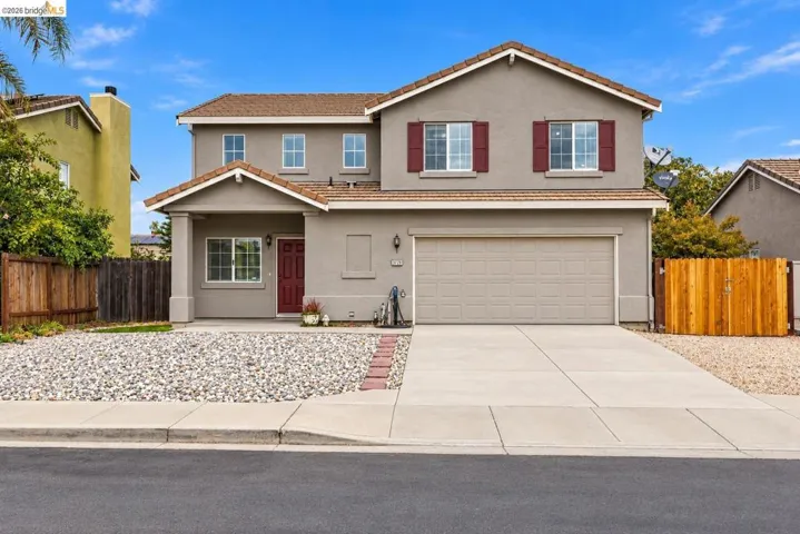 Two-story residence featuring a stucco exterior, concrete tile roof, attached two-car garage, red shutter accents, and a low-maintenance gravel front landscape