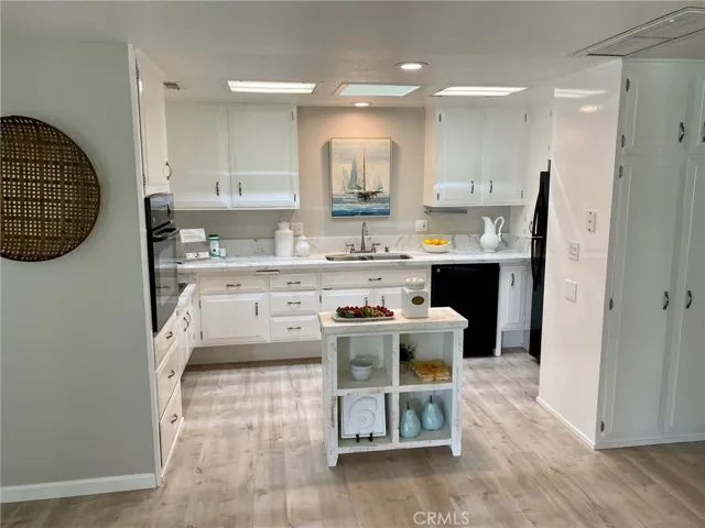 Light, bright sleek, modern kitchen has a dishwasher, microwave above cooktop, new sink, faucet, quartz countertops, hardware, and new recessed lights.
