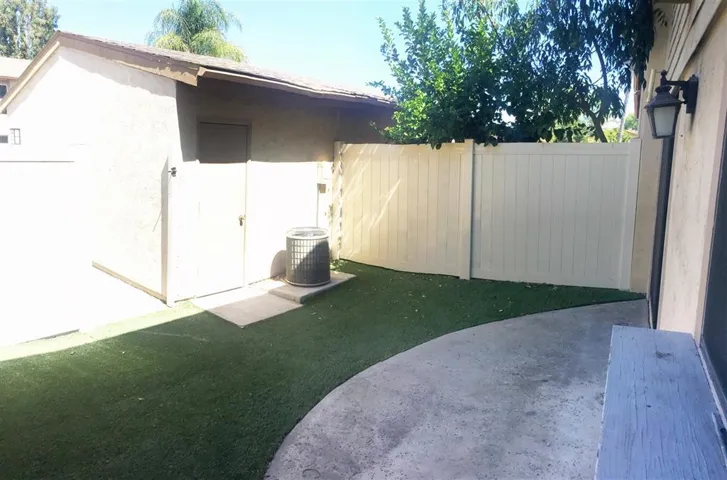 Back patio with artificial grass leading to garage.
