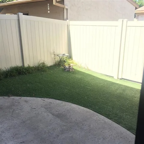 Back patio with artificial grass leading to garage.