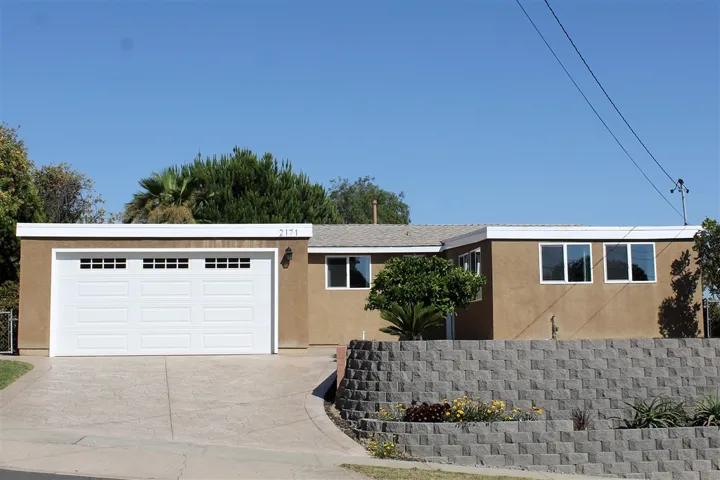 Corner lot - front of home with fruit trees, stamped concrete driveway, and 2-car garage!