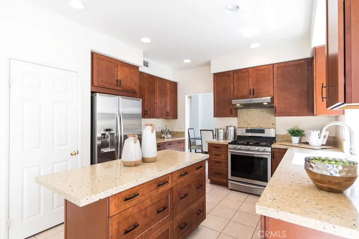 Quartz stone counters and rich toned shaker style cabinetry warm up the spacious kitchen