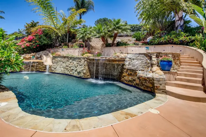 Tropical paradise with this pool, pool slide, water falls & jacuzzi!. Pathways surrounded by numerous tropical plants, fruit trees & flowers.