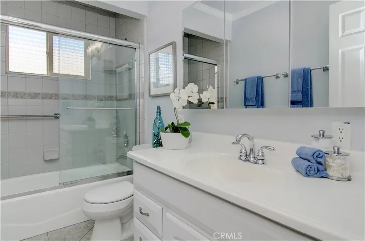 Sparkling hall bath has vanity with storage and beautiful tile accents.