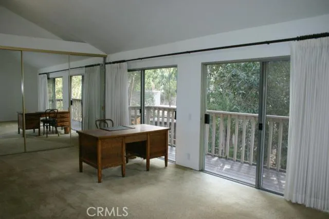 This is the sitting area of the master bedroom with some of the closets. Two sets of sliding glass doors open to the balcony and a tree top view
