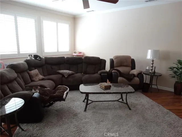 Family room open to the kitchen features a fireplace, tv alcove, crown molding, plantation shutters and laminate flooring.