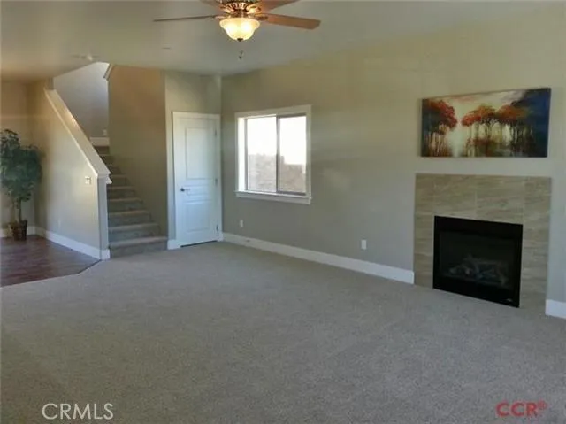 Great Room with tile bordered gas fireplace, ceiling fan and wide baseboard throughout home.