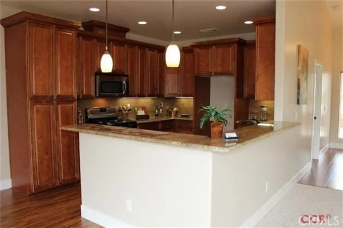Kitchen with breakfast bar, mocha maple cabinets with crown molding and engineered wood flooring